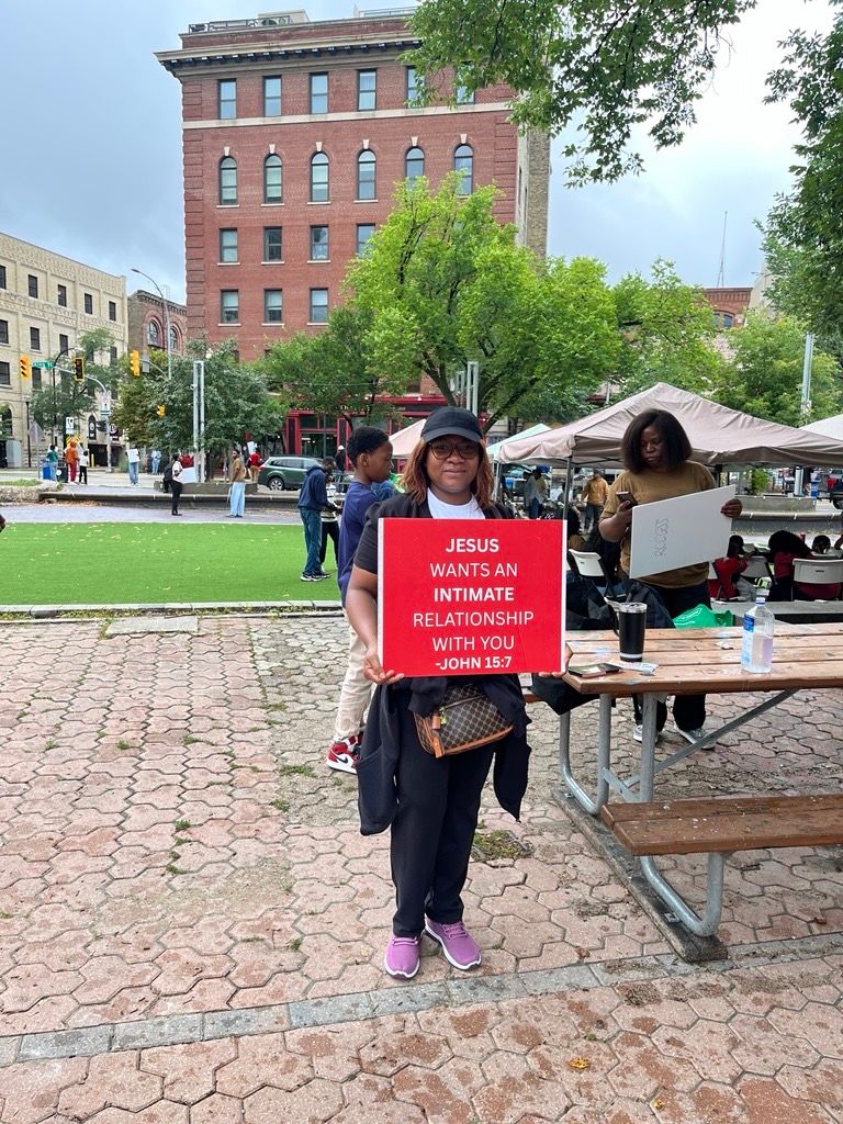 a woman holding a red sign that says Jesus wants a relationship with you